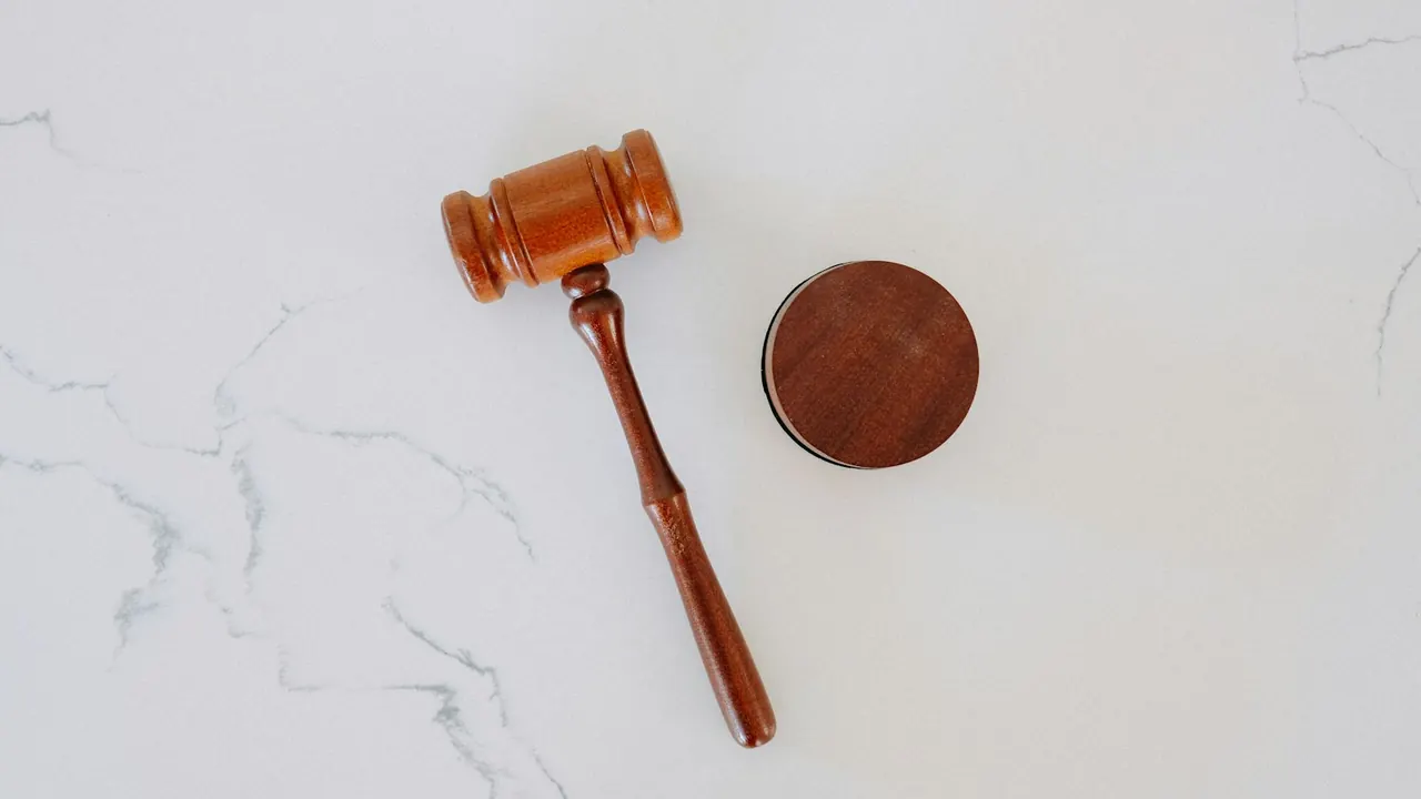 Marteau de juge en bois posé sur une table en marbre blanc
